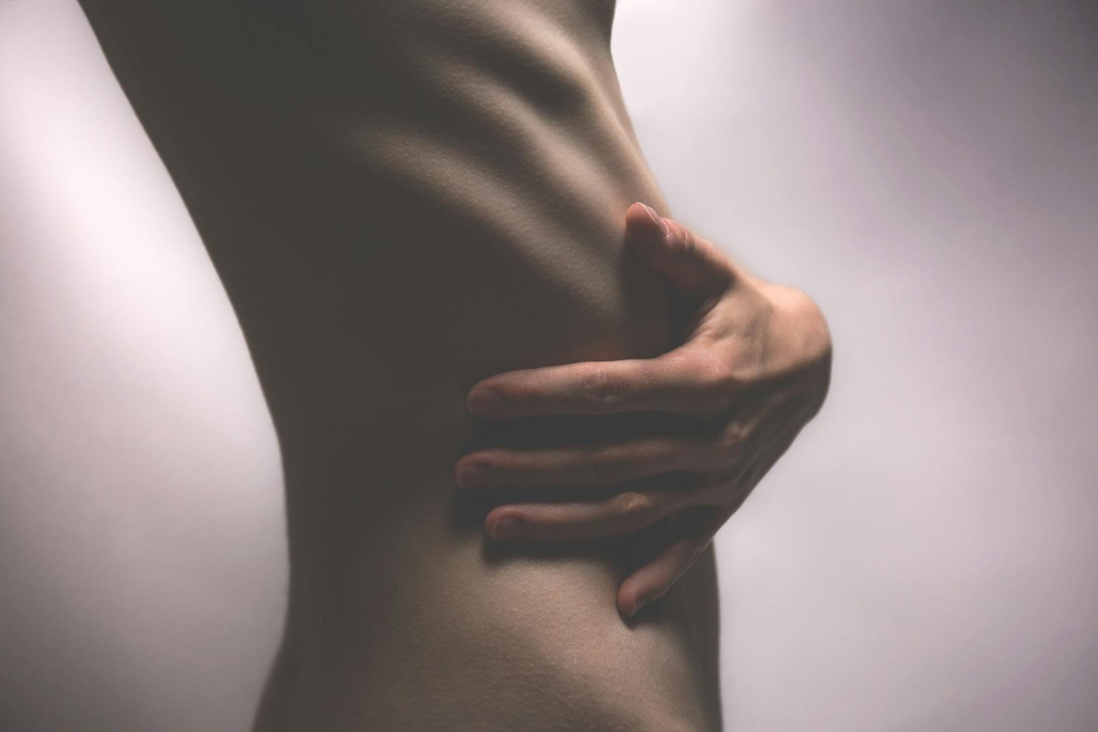 side view photo of person touching stomach