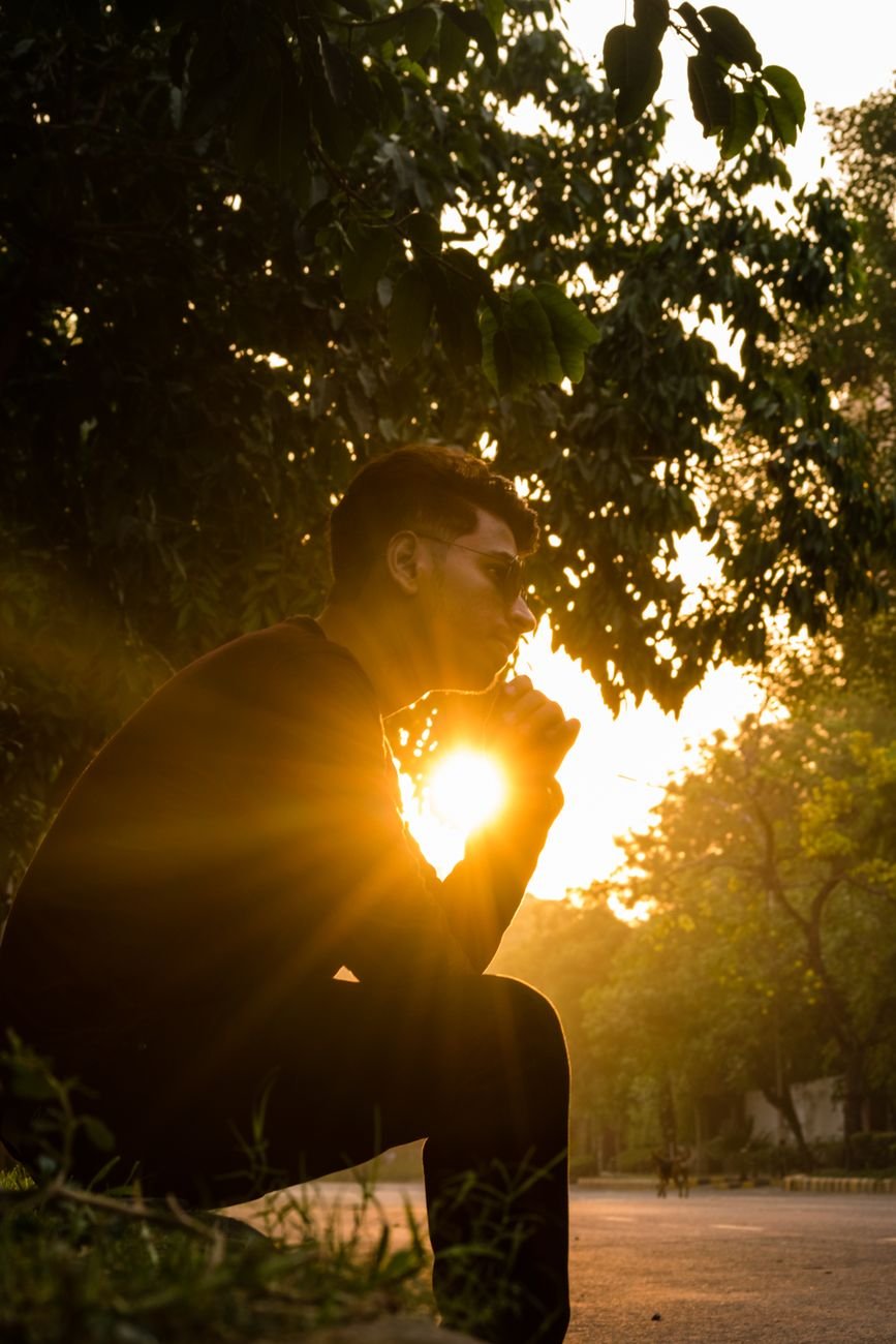 man sitting on grass near tree