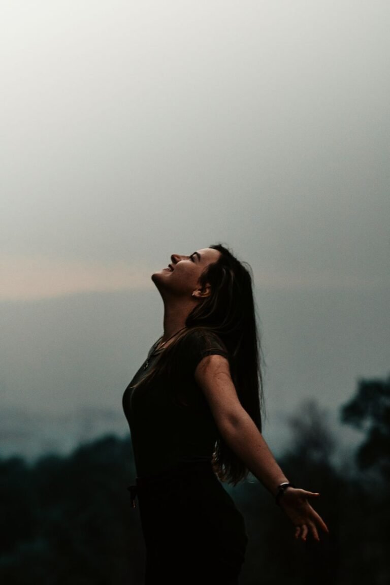 woman with arms apart looking up in the sky