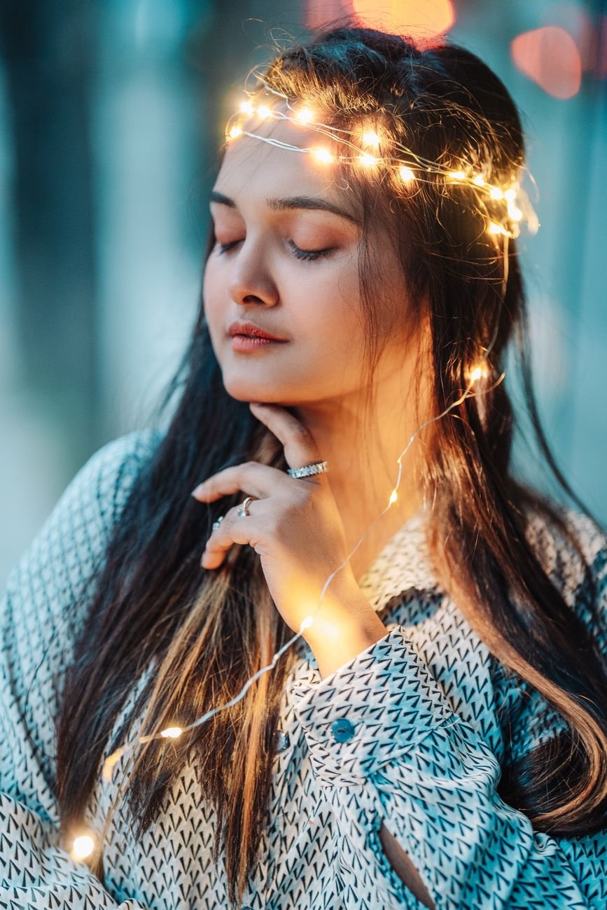 close up photo of woman with string lights on her head