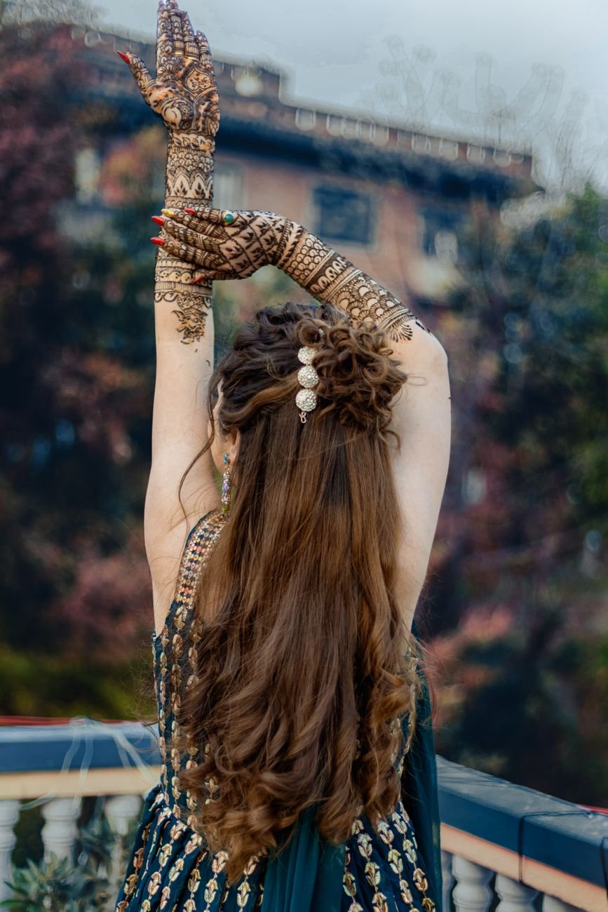 back view of a woman with mohendi paint on her hands standing on a balcony