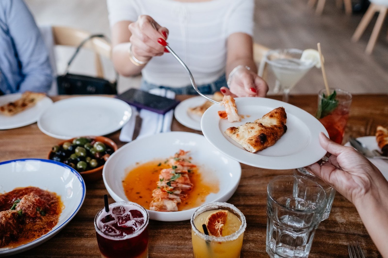 woman passing food to the other person at the table in a restaurant