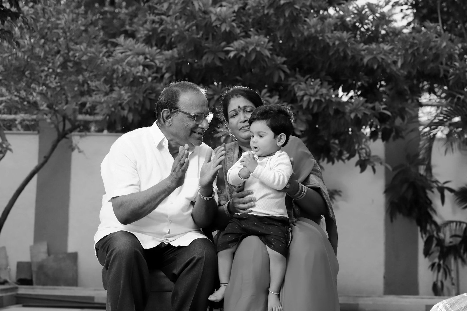 smiling man and woman sitting with child in black and white