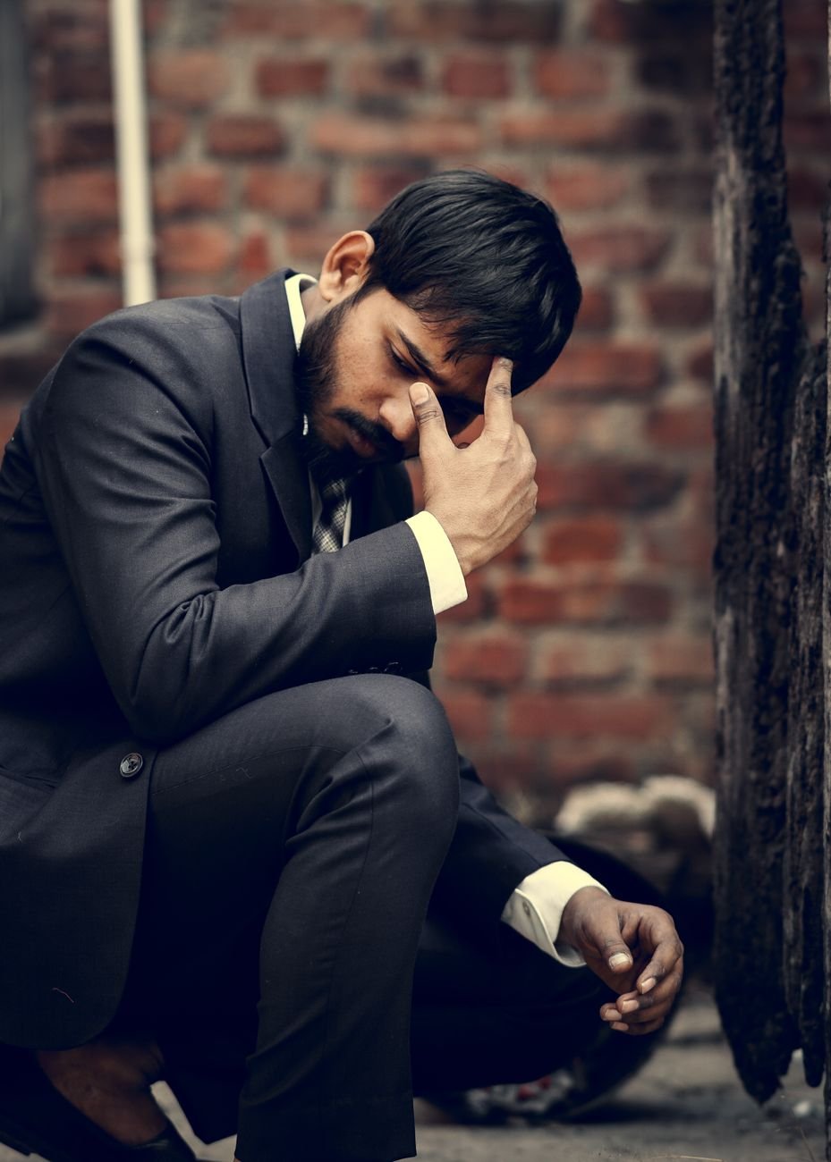 man wearing suit kneeling on street