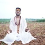 a man in white sitting in the middle of a field