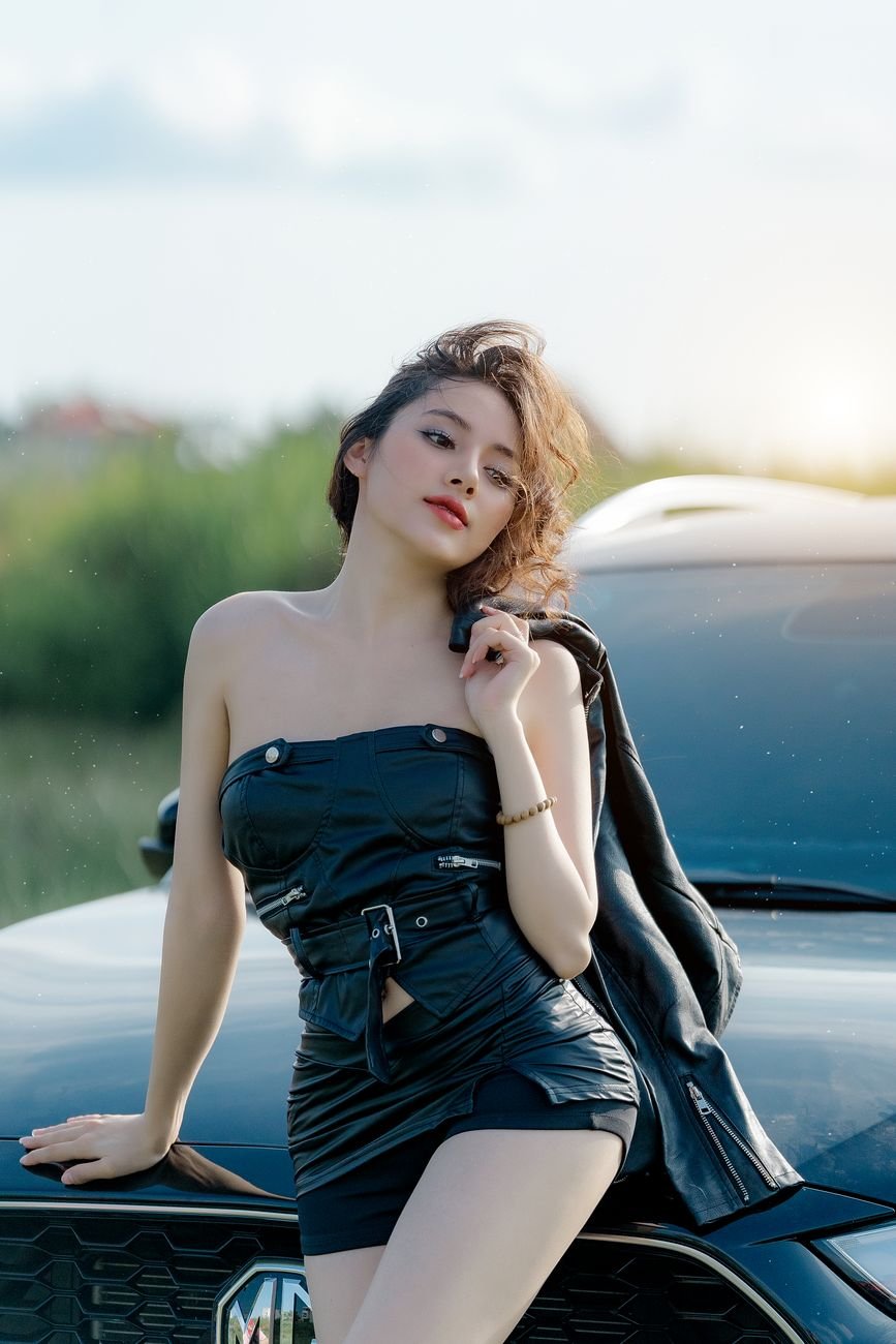 stylish woman posing by car in nature