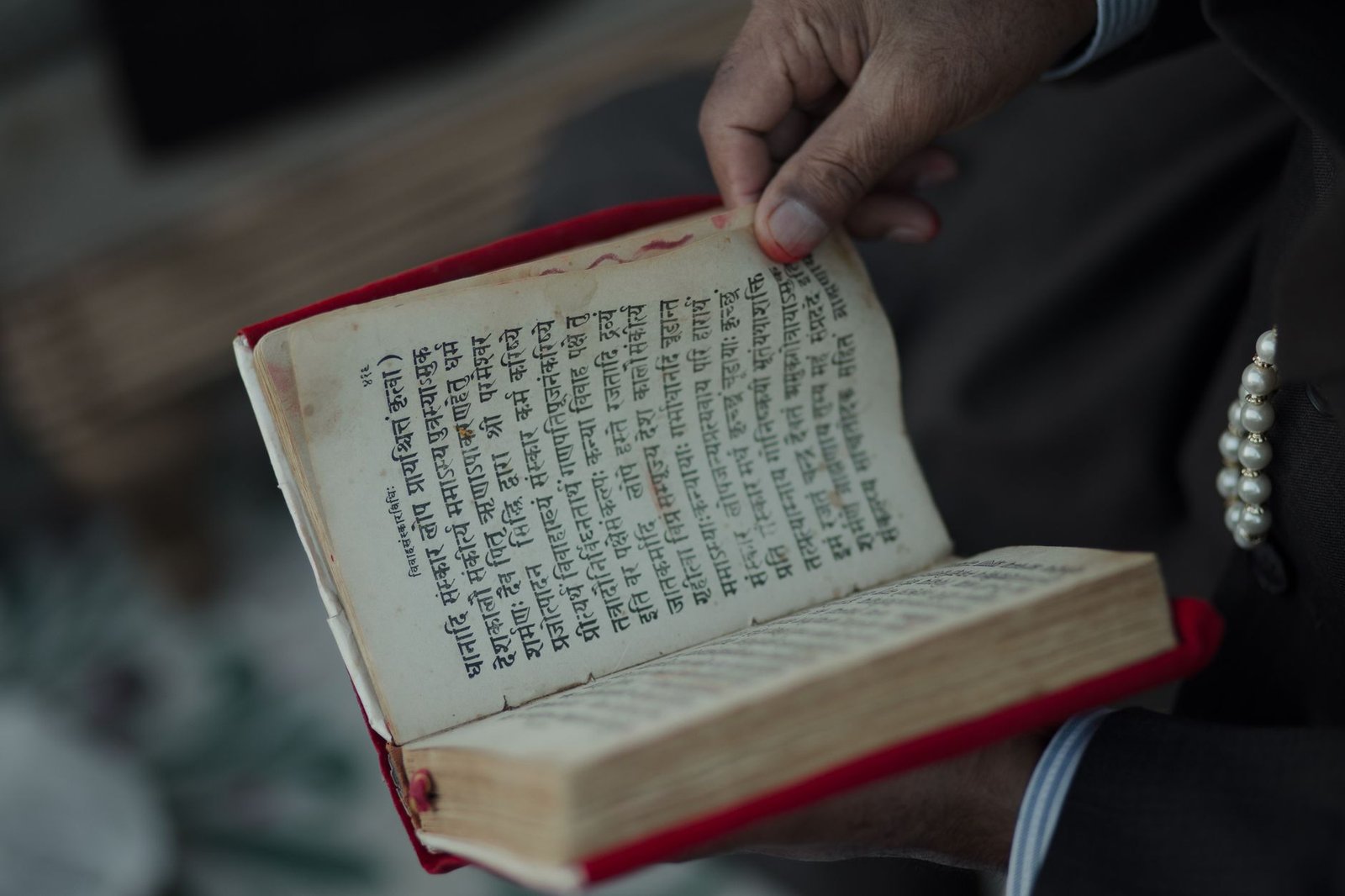 close up of hand holding ancient sanskrit text