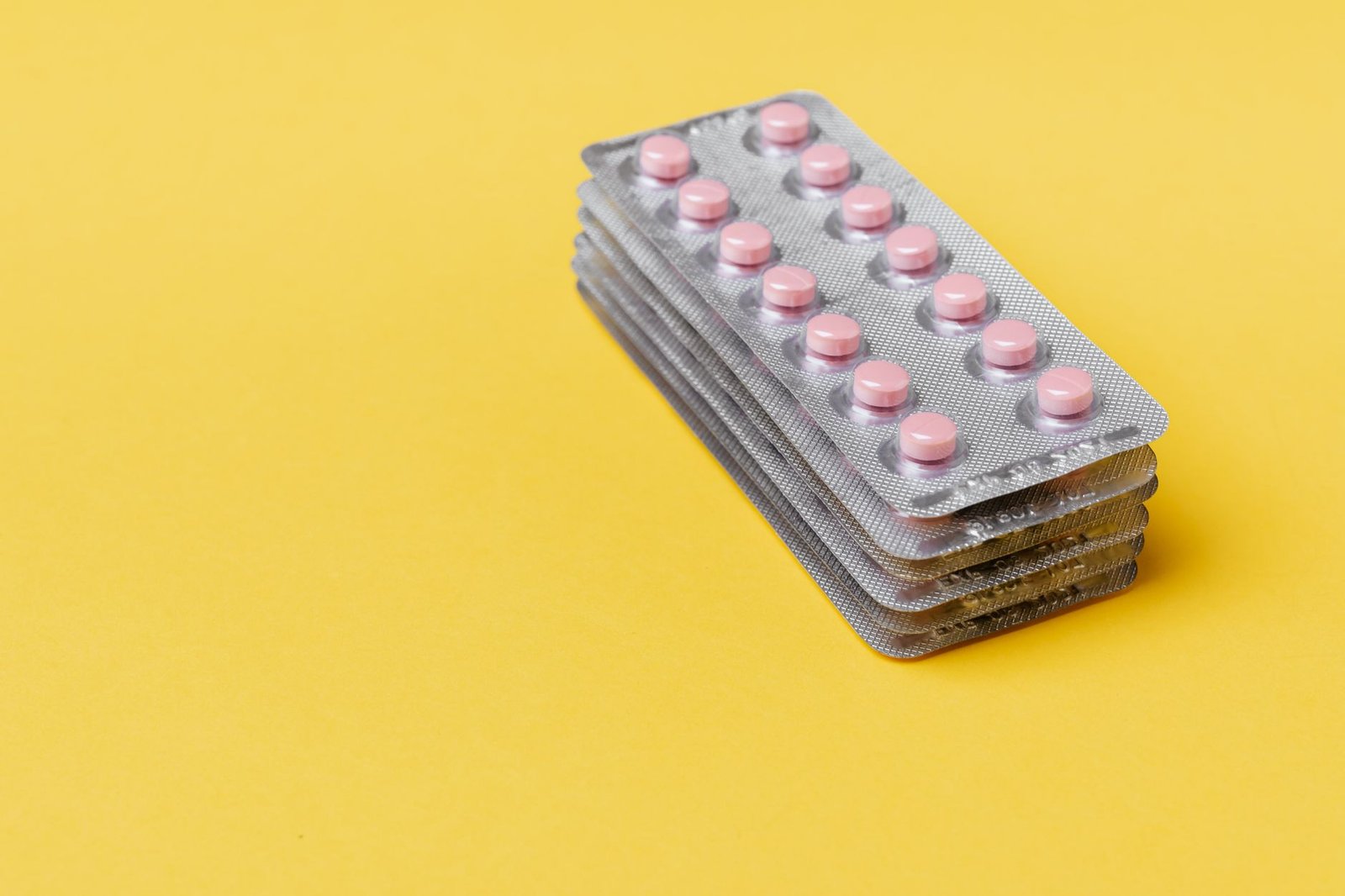 stack of pink capsules on blister packs