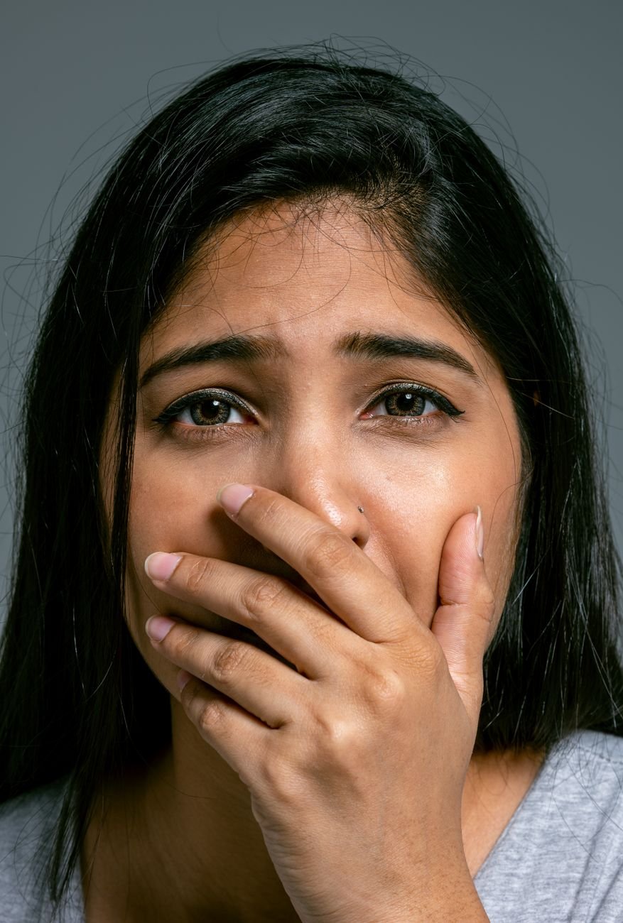 close up portrait of terrified woman covering mouth with hand