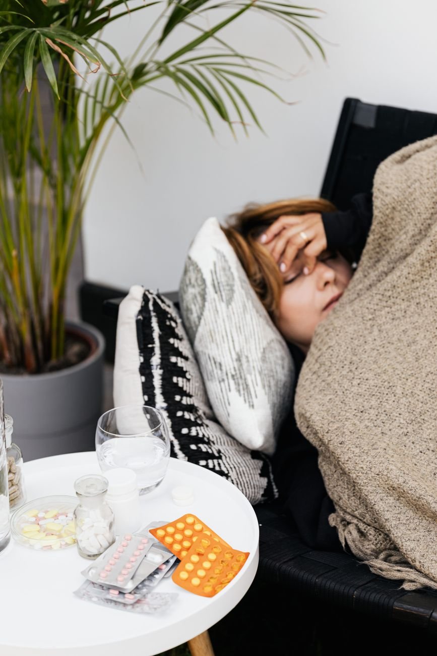 medications lying on table by ill woman on sofa