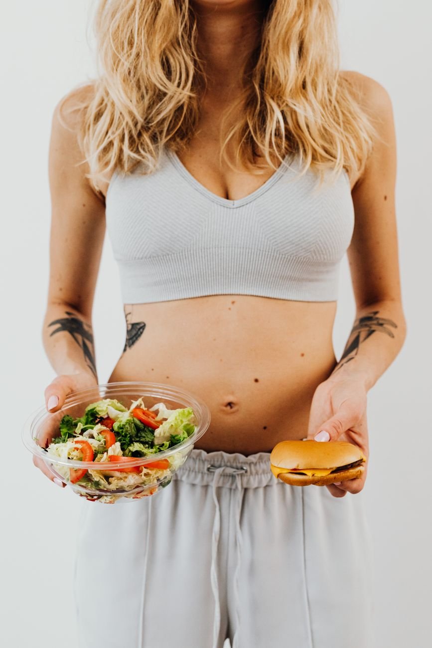 woman holding burger and bowl of salad