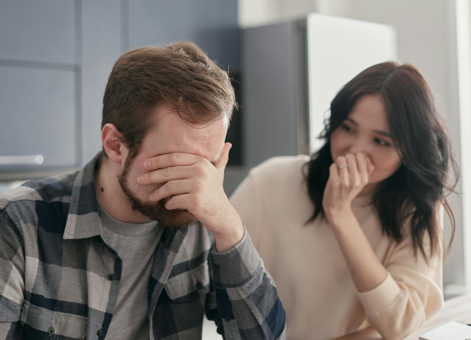 man in a plaid shirt covering his face