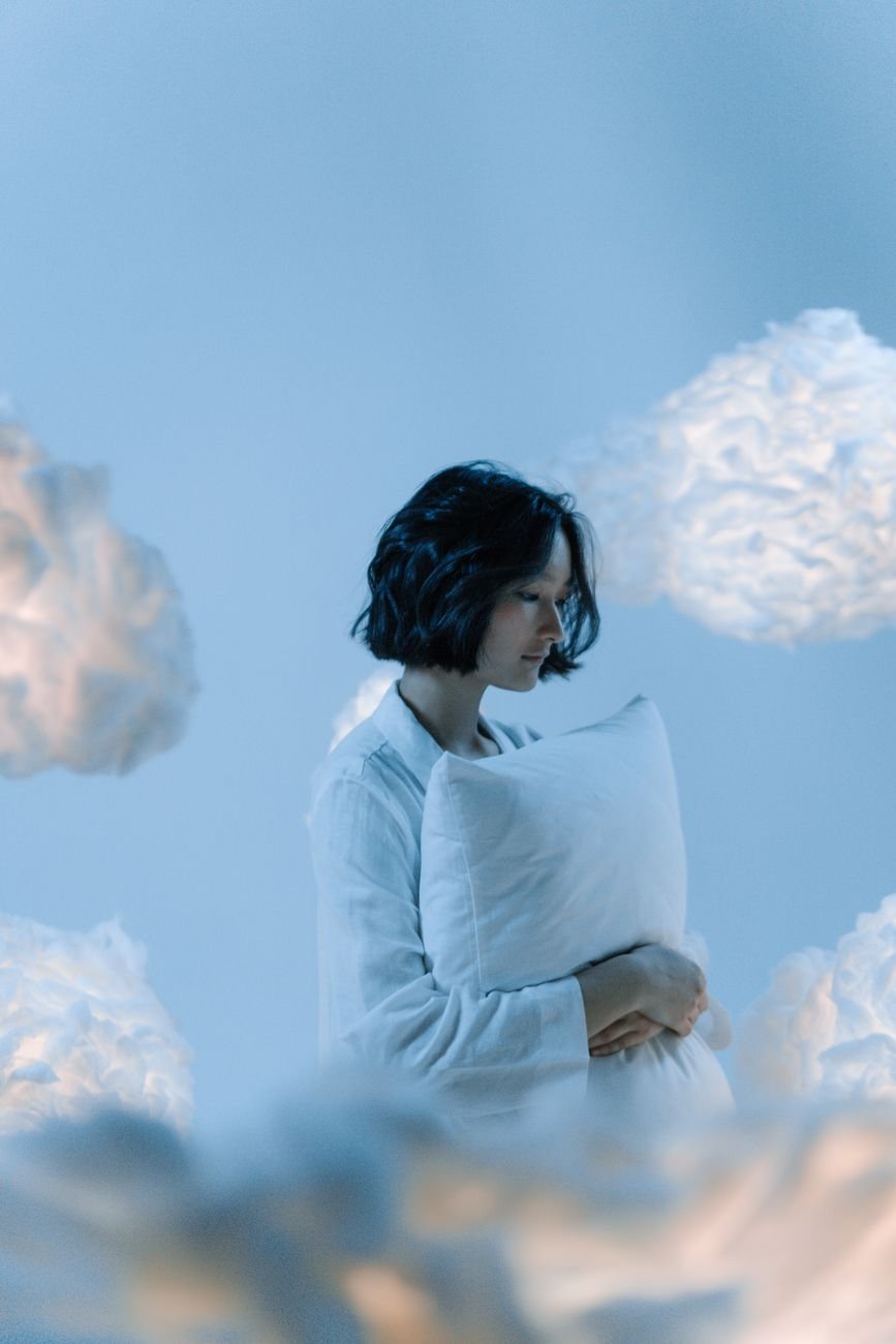 a woman in white long sleeves embracing a pillow