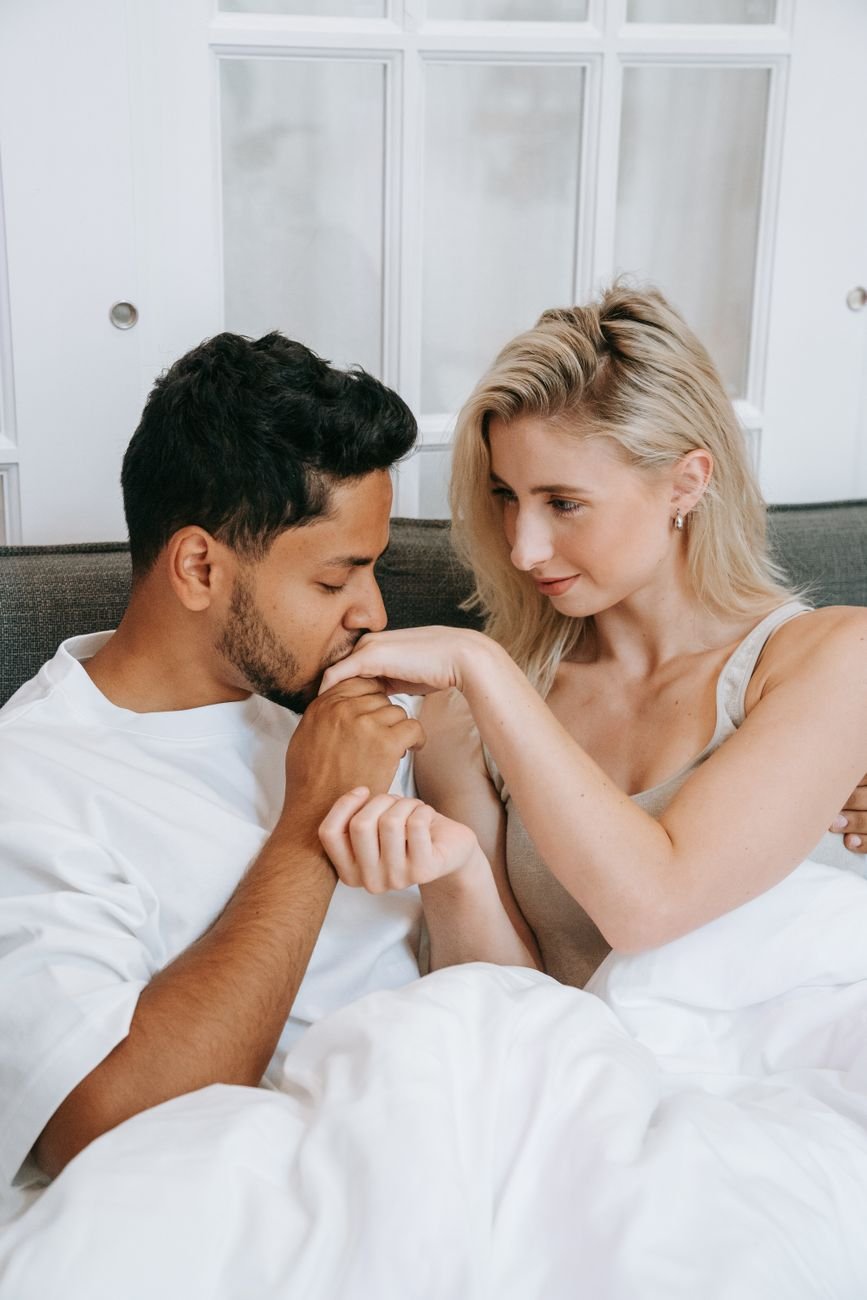 man in white shirt kissing woman in white sleeveless dress