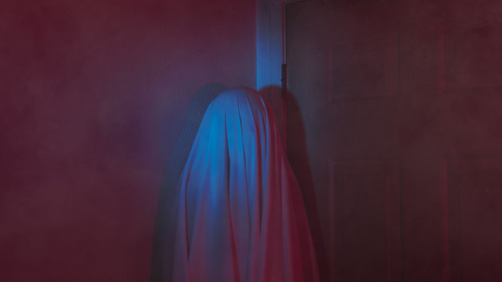 a mysterious object covered by a sheet against a wall in a dark interior