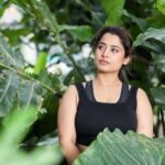 elegant woman posing among lush green foliage
