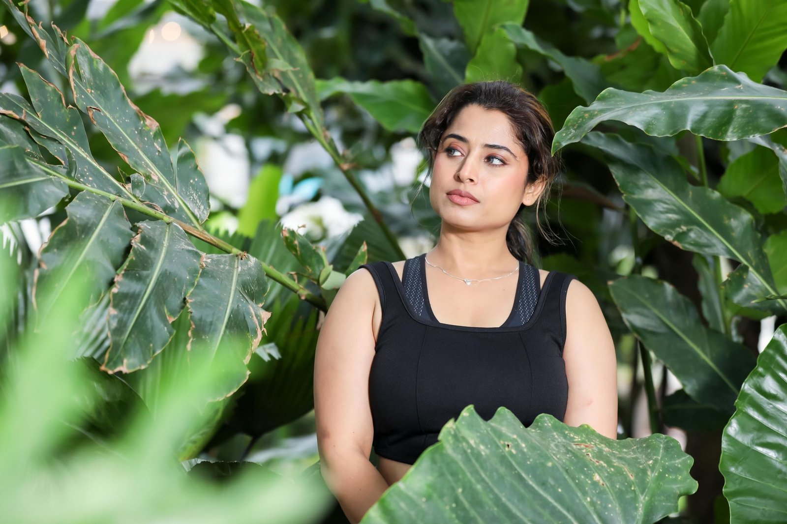 elegant woman posing among lush green foliage