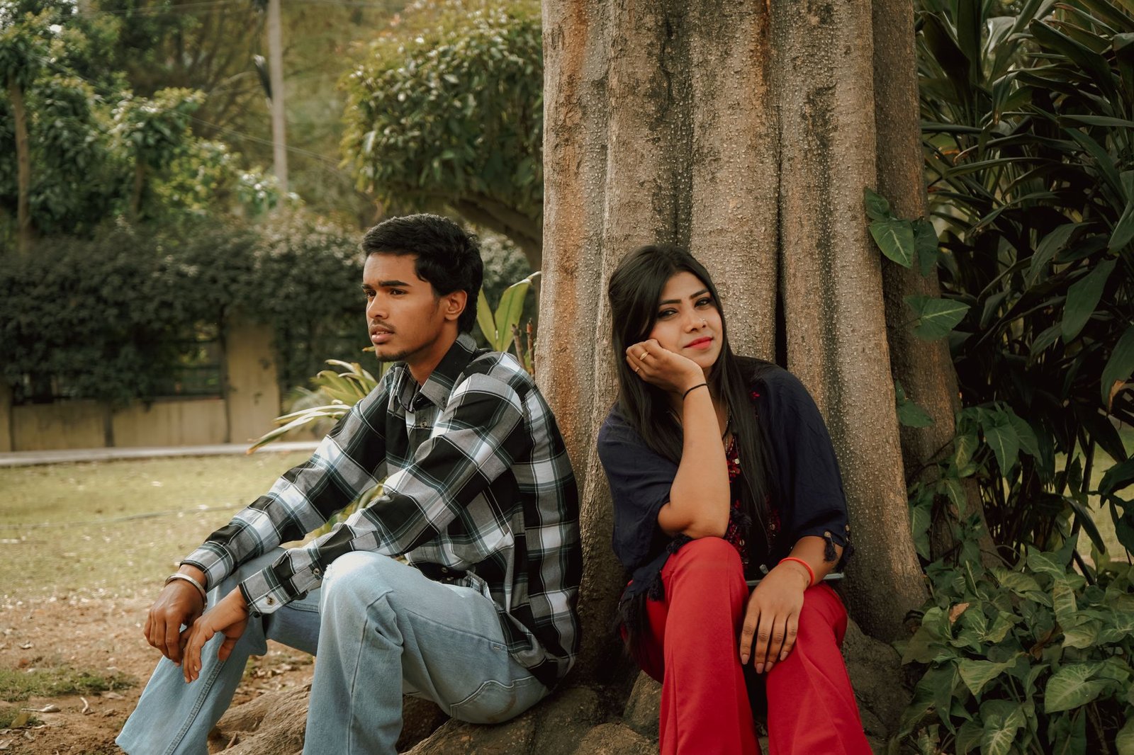 young couple in thoughtful pose by a tree outdoors