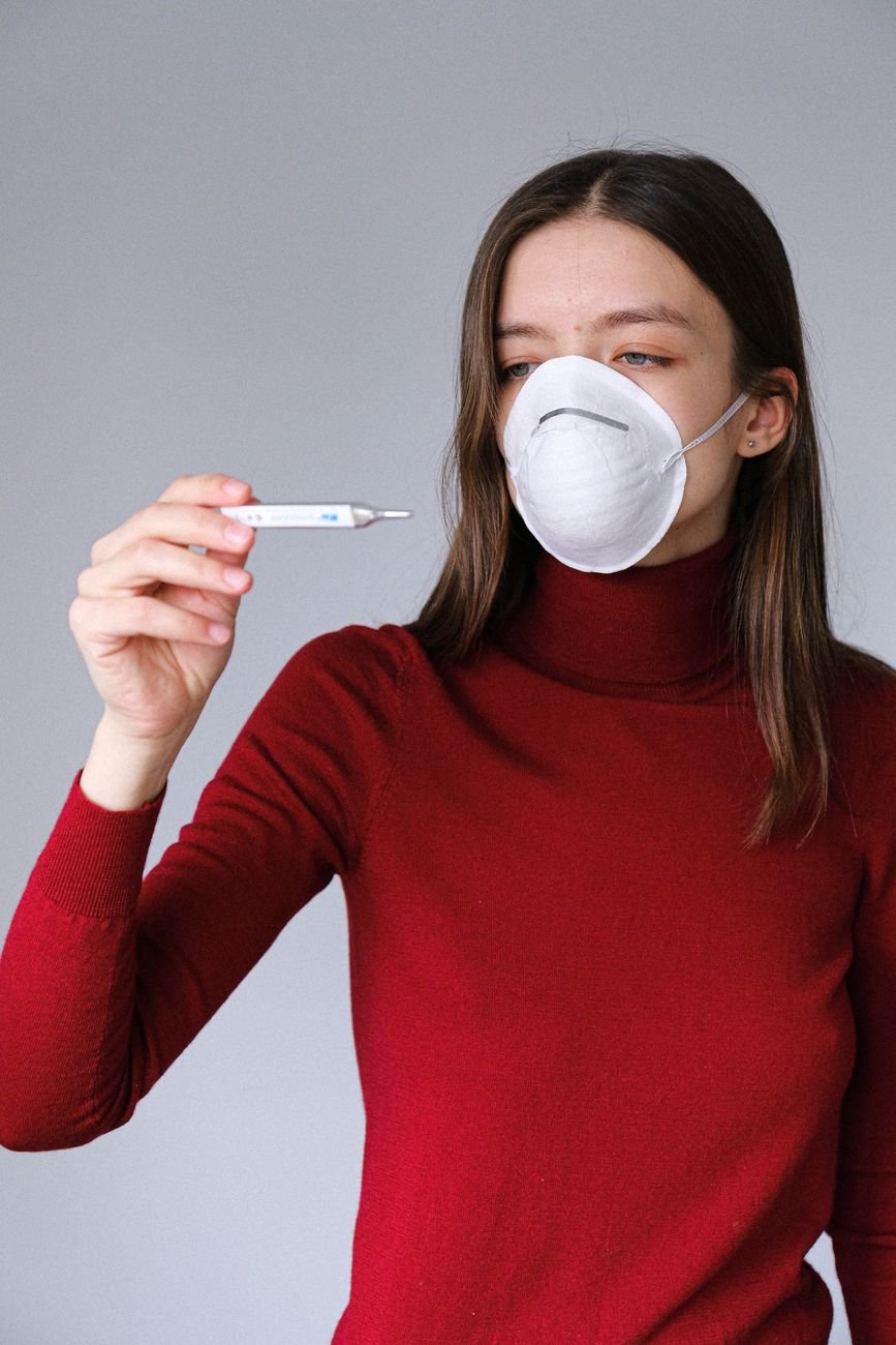 woman in face mask checking thermometer