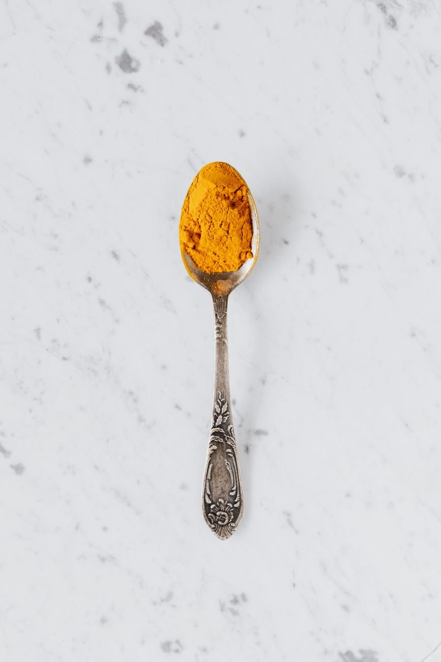 yellow turmeric powder on silver spoon