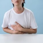 man in white shirt suffering from a stomach pain