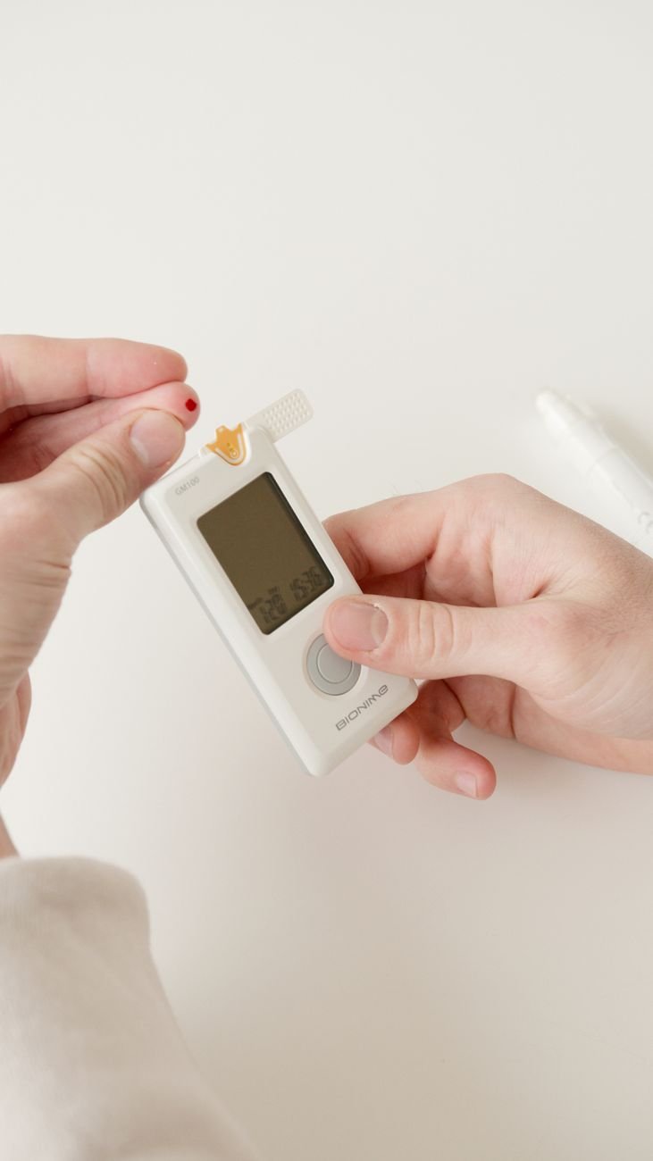 a finger with blood beside glucometer