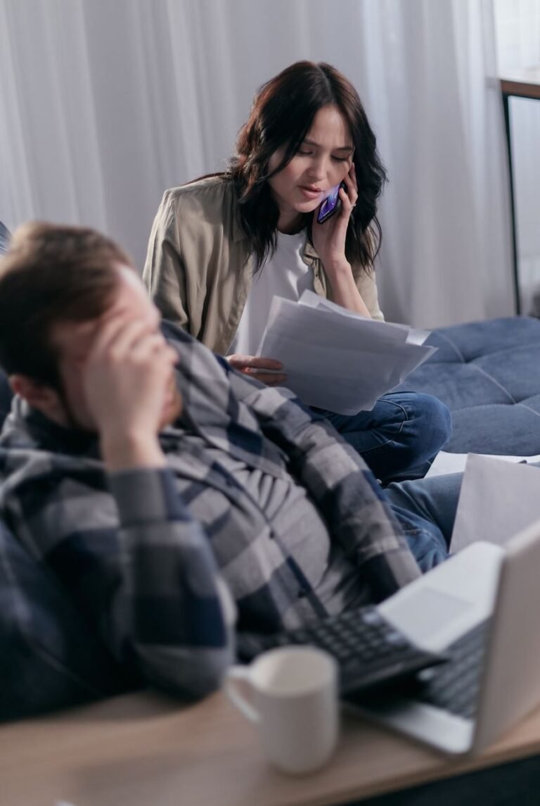 woman on the phone holding paperwork beside a man in deep thoughts