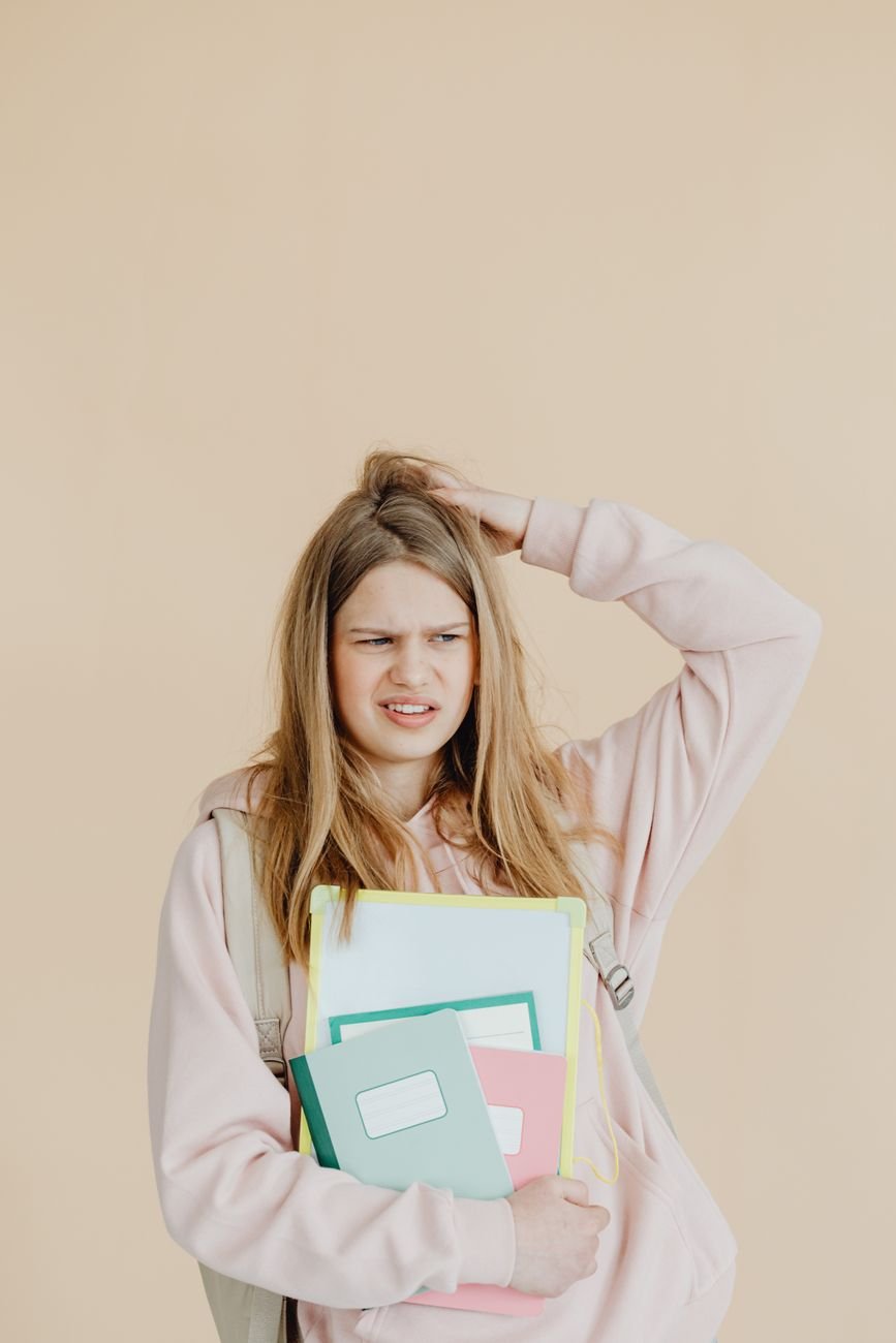 a woman in beige long sleeves holding notebooks