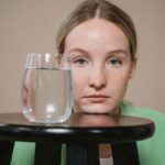 clear drinking glass with liquid near the woman s face