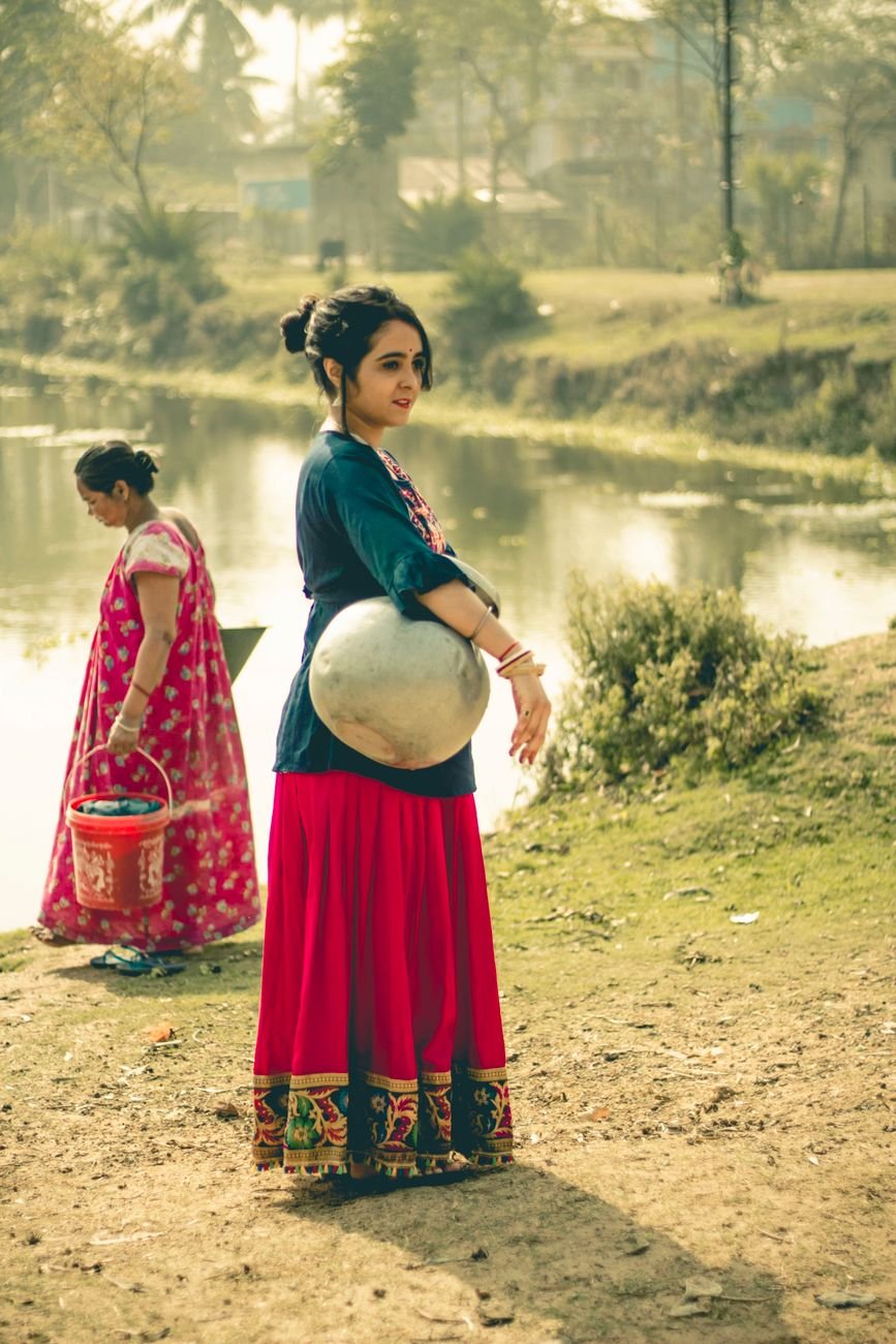 woman carrying a jar while standing near a river