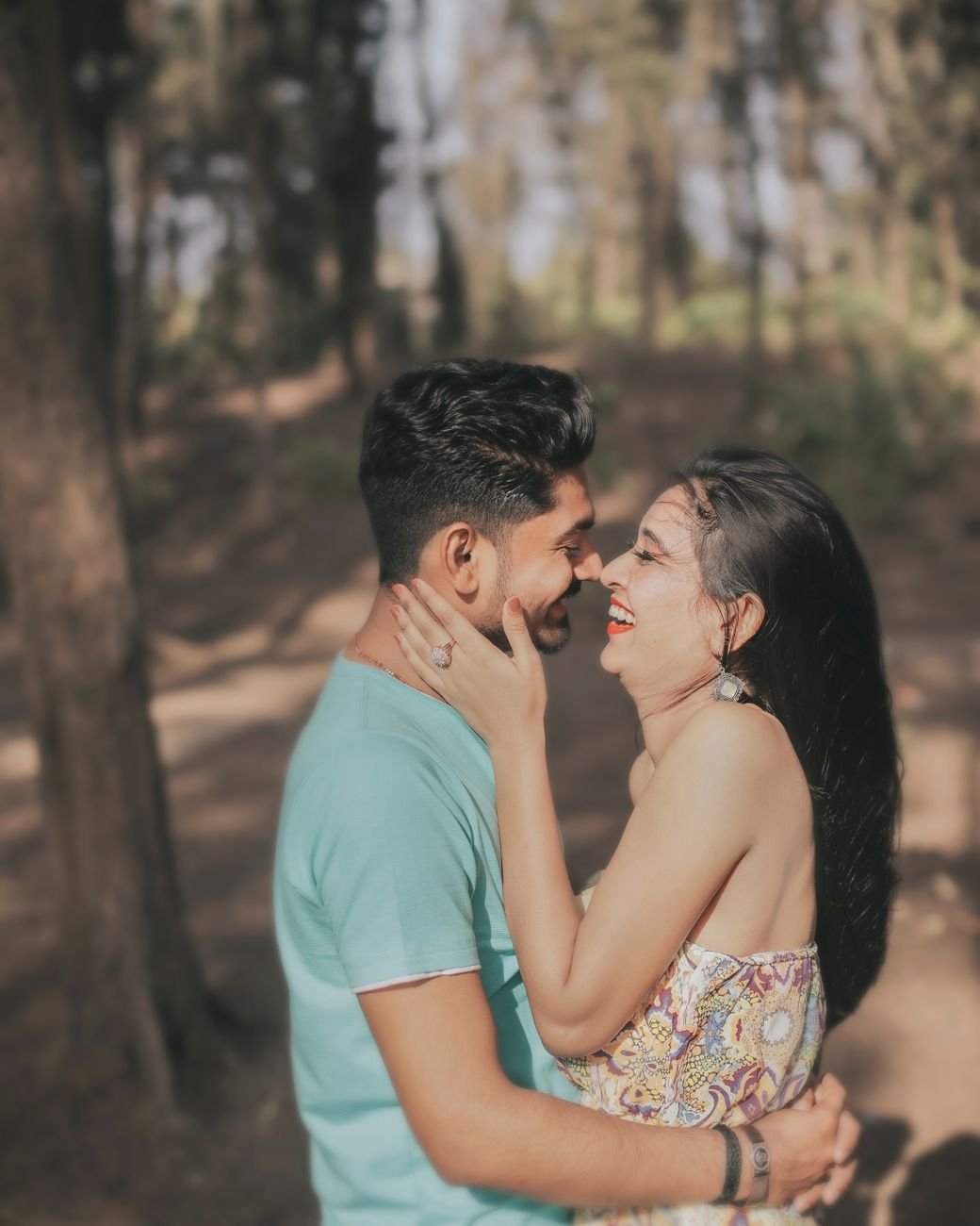 man and woman kissing in the forest