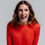 woman in orange long sleeve shirt feeling irritated