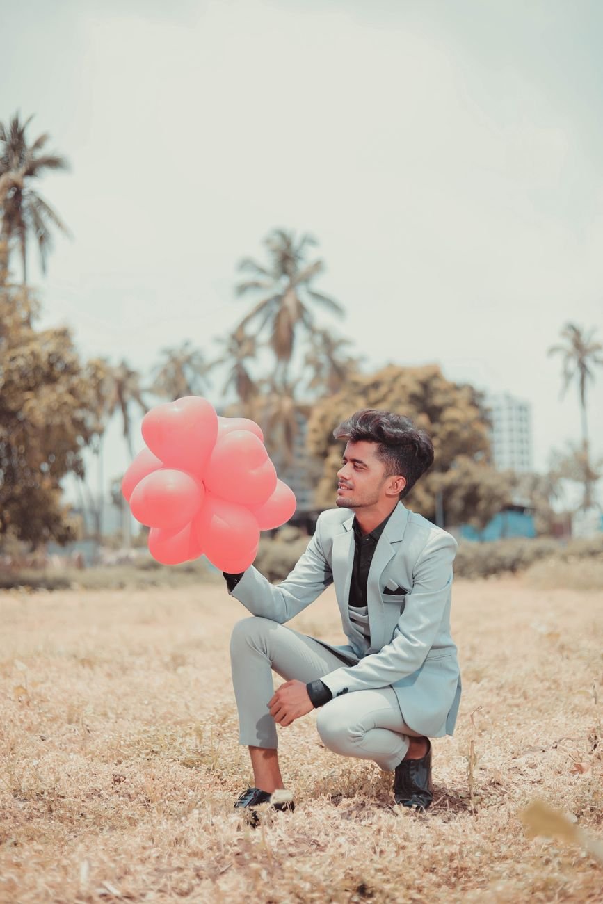 a man in a suit holding heart shaped balloons