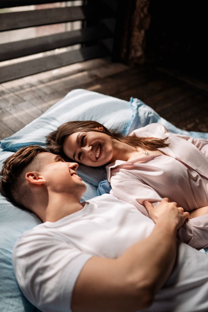 young couple lying on bed and looking at each other