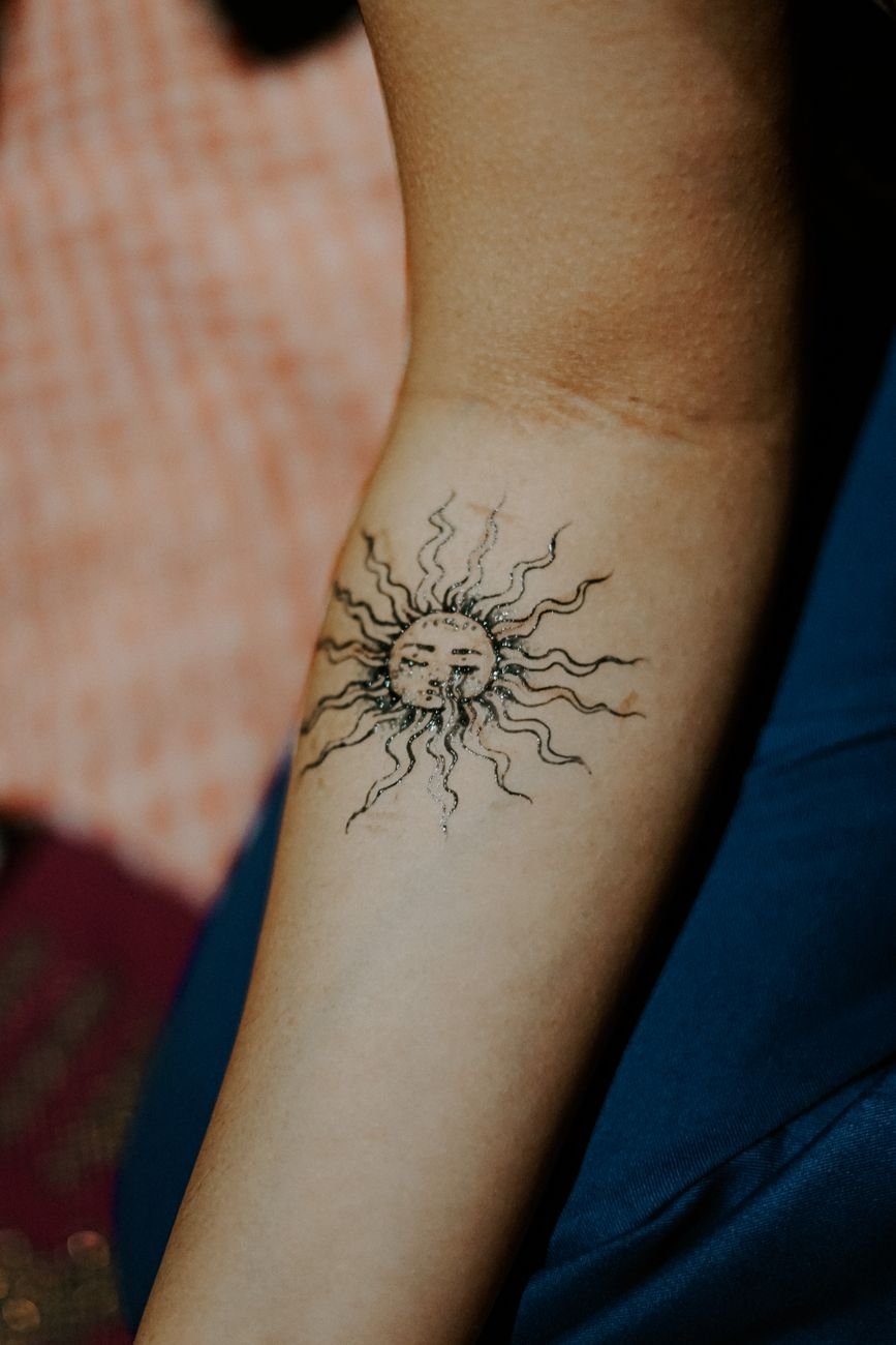 black sun tattoo on person s arm