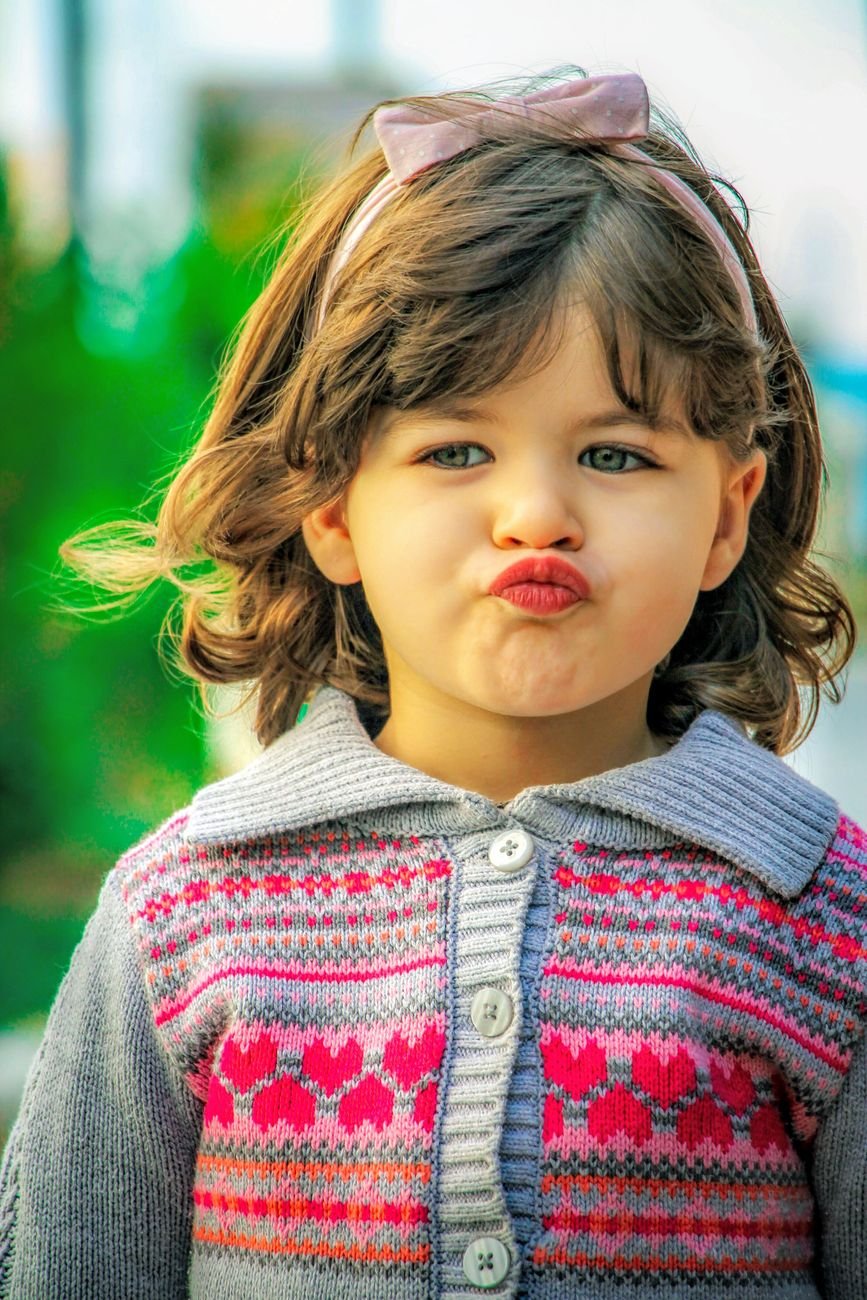 close up of a cute toddler in a sweater and hair bow