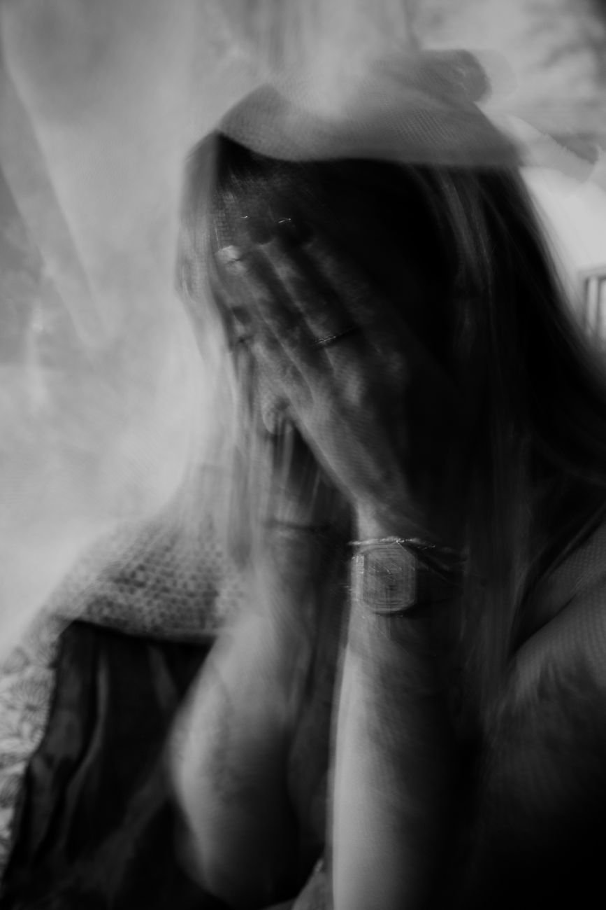 grayscale photo of woman covering face with her hands