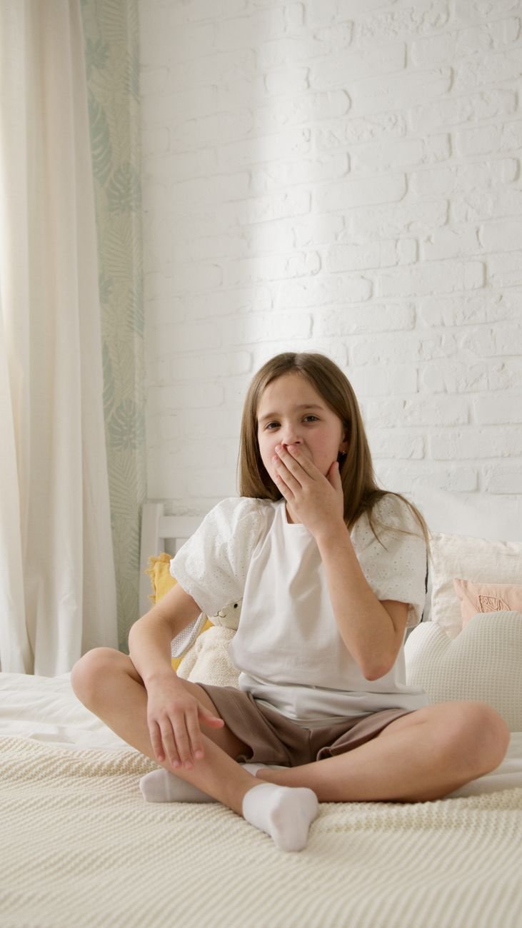 girl sitting on bed yawning