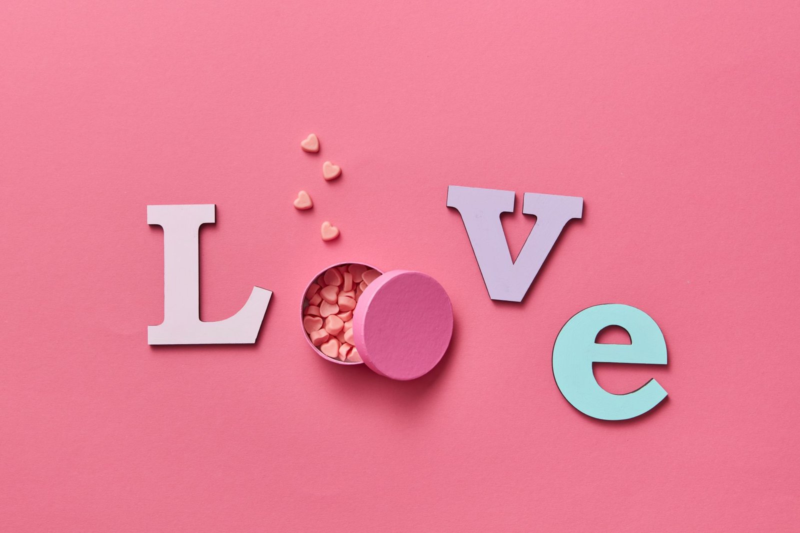 heart candies and letter cutouts on a pink surface