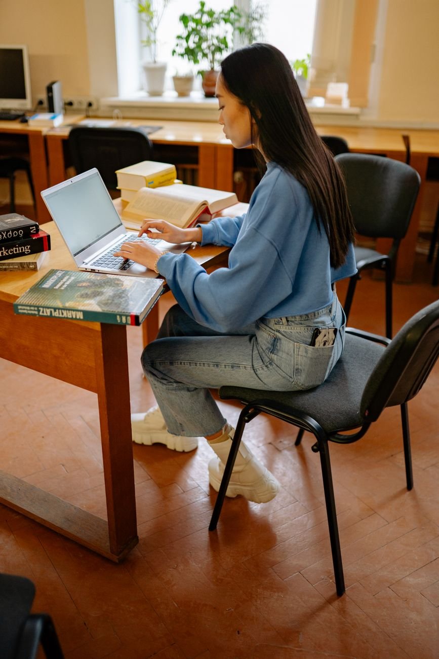 a woman in a blue sweater typing on a laptop