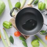 cooking pot with oil surrounded by fresh vegetables