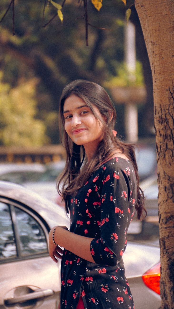 young woman in a blouse with a floral pattern standing near a car outside